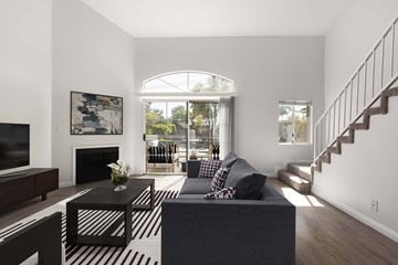 Los Angeles townhouse for rent - A living room with a grey couch and a black and white striped rug.