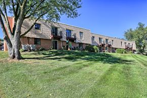 Shippensburg apartment for rent - A tree stands in front of a brick building with a lawn in the foreground.