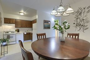 Harrisburg apartment for rent - Apartments in Harrisburg | Twin Lakes Apartments | a dining area with a wooden table and chairs and a kitchen in the background