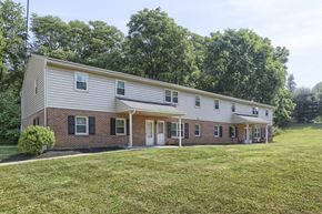 York apartment for rent - a white and brick house with a green lawn and trees