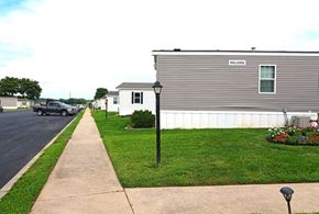 Ephrata apartment for rent - A grey house with a white fence and a green bush in front.