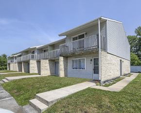 Etters apartment for rent - an exterior view of a white and gray apartment building with a sidewalk and grass