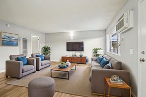 Lake Balboa apartment for rent - A living room with a grey couch, a coffee table, and a flat screen TV mounted on the wall.