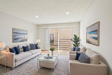 North Hollywood apartment for rent - A living room with a white couch, a glass coffee table, and a painting on the wall.