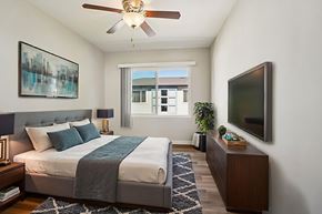 Los Angeles apartment for rent - A bedroom with a bed, a ceiling fan, a nightstand, a plant, and a television.