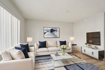 Hawthorne apartment for rent - A modern living room with white furniture and a large abstract painting on the wall.
