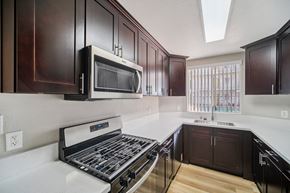 Canoga Park apartment for rent - A kitchen with dark brown cabinets and a white counter top.