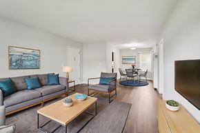 Inglewood apartment for rent - A living room with a grey couch, a wooden coffee table, and a painting on the wall.