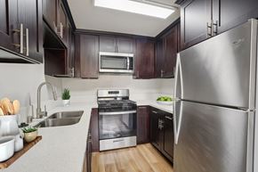 Hawthorne apartment for rent - A modern kitchen with dark wood cabinets and stainless steel appliances.