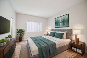 Canoga Park apartment for rent - A bedroom with a bed, nightstand, and a plant.