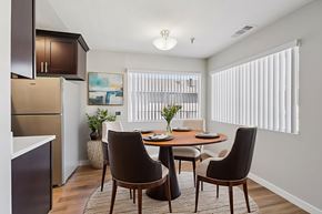 Hawthorne apartment for rent - A dining room with a table set for two and a refrigerator in the corner.