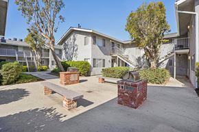 Hawthorne apartment for rent - A courtyard with a bench and a tree in front of apartment buildings.