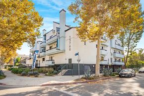 Van Nuys apartment for rent - A modern building with a white facade and a blue sign on the front.