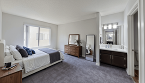Van Nuys apartment for rent - A bedroom with a large bed and a vanity with a mirror.