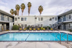 Van Nuys apartment for rent - A swimming pool in front of a building with palm trees in the background.