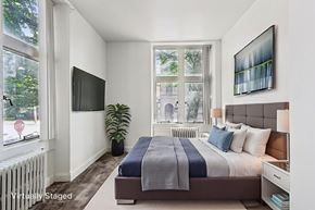 New Kensington apartment for rent - A bedroom with a large bed and a flat screen TV mounted on the wall.