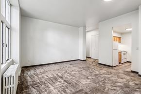 New Kensington apartment for rent - A spacious, empty room with a carpeted floor and a radiator on the left side.