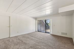 White Oak apartment for rent - A spacious room with a carpeted floor and a sliding glass door leading outside.