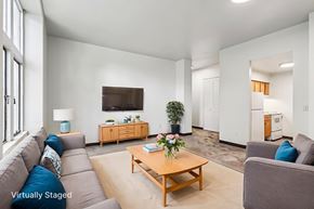 New Kensington apartment for rent - A living room with a grey couch, a wooden coffee table, and a flat screen TV mounted on the wall.