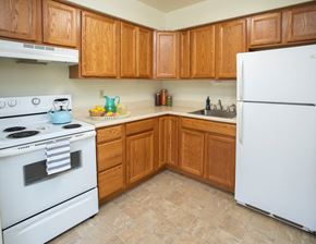 Butler apartment for rent - A kitchen with wooden cabinets and a white stove and refrigerator.