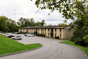 Wilkins Twp apartment for rent - A curved driveway leads to a building with a parking lot in front.