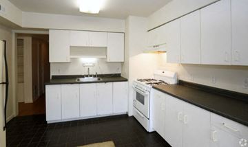 Michigan City apartment for rent - A kitchen with white cabinets and black countertops.