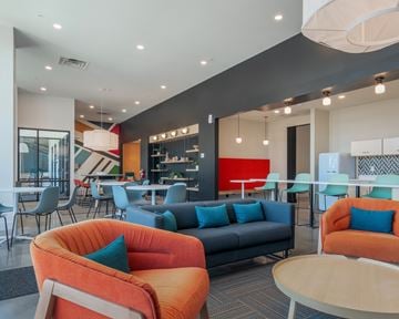Evansville apartment for rent - A modern living room with orange chairs and a grey couch.