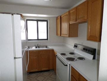 Michigan City apartment for rent - A kitchen with a white stove top oven and a white refrigerator.
