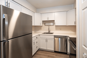 Michigan City apartment for rent - A kitchen with a stainless steel refrigerator and white cabinets.