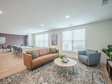 Evansville apartment for rent - A living room with a brown couch and a round table with a plant on it.