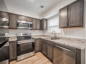 Evansville apartment for rent - A kitchen with dark wood cabinets and stainless steel appliances.