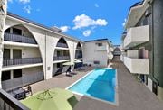 Los Angeles apartment for rent - A swimming pool is surrounded by a concrete floor and a green umbrella. at Bonnie Brae Apartments, California, 90006