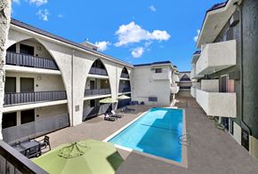 Los Angeles apartment for rent - A swimming pool is surrounded by a concrete floor and a green umbrella. at Bonnie Brae Apartments, California, 90006