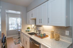 Richmond apartment for rent - A kitchen with white cabinets and a marble countertop.
