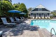 Stratford apartment for rent - A pool area with lounge chairs and umbrellas in front of a house.