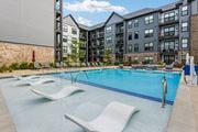 Cranberry Township apartment for rent - A swimming pool with lounge chairs and a building in the background.