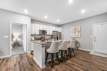 A kitchen with white cabinets and a counter top with chairs