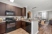 Shelton apartment for rent - A kitchen with dark wood cabinets and a black oven. at Merion Riverwalk Apartment Homes, Shelton, CT, 06484
