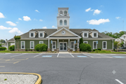 Millsboro apartment for rent - Clubhouse and a clock tower is surrounded by a parking lot.