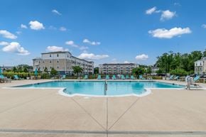 Millsboro apartment for rent - A large swimming pool in the middle of a sunny day with people around it.