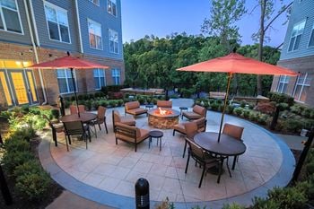 A patio with tables and umbrellas and a fire pit