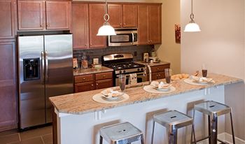 A kitchen with a refrigerator, stove, and bar stools.