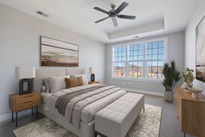 Pennsauken apartment for rent - A bedroom with a large bed, a ceiling fan, and a painting on the wall.