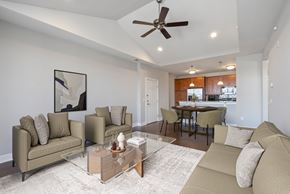 Pennsauken apartment for rent - A living room with a beige couch, a glass coffee table, and a ceiling fan.