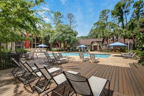 Jacksonville apartment for rent - A pool surrounded by chairs and trees.