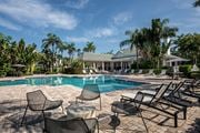 Bradenton apartment for rent - a swimming pool with chairs and a house in the background at Champions Walk Apartment Homes, Bradenton, Florida