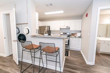 A kitchen with white cabinets and a counter top with two stools