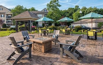 A patio with chairs and umbrellas and a fire pit