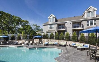 A swimming pool with chairs and umbrellas in front of a house