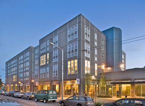 Seattle apartment for rent - A modern multi-story building with cars parked in front.
